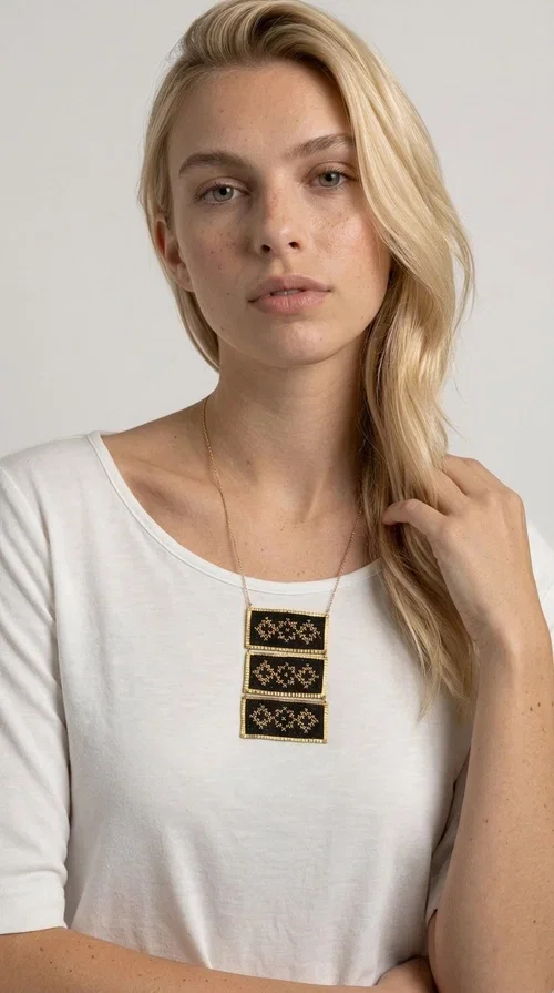 , An embroidered necklace that combines traditional Greek aesthetics with modern fashion — the Statement necklace KOL-4774 is a handmade creation that instantly catches the eye.

Designed by Greek Jewelry Designer Aikaterini Chalkiadaki, this necklace features three rectangular fabric plaques in deep black, adorned with gold-toned embroidered geometric designs inspired by Greek folk tradition. The frame of each plaque, made of gold-toned brass, gives the piece a rich, striking presence. The accompanying brass chain keeps the composition light on the neck, while the overall look exudes a unique blend of ethnic and contemporary style.

Ideal for women who love statement jewelry and want to elevate simple outfits — a linen shirt, a black dress, or even a casual look — with a wonderful touch of individuality. Perfect for nights out, events, weddings, or everyday wear when you want to stand out.