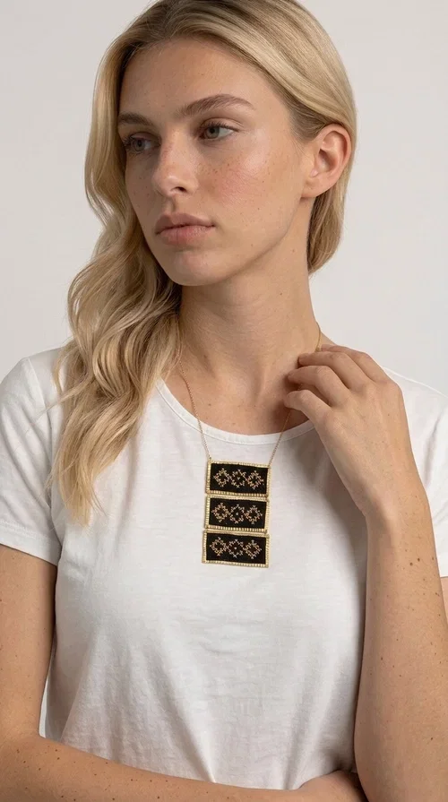 , An embroidered necklace that combines traditional Greek aesthetics with modern fashion — the Statement necklace KOL-4774 is a handmade creation that instantly catches the eye.

Designed by Greek Jewelry Designer Aikaterini Chalkiadaki, this necklace features three rectangular fabric plaques in deep black, adorned with gold-toned embroidered geometric designs inspired by Greek folk tradition. The frame of each plaque, made of gold-toned brass, gives the piece a rich, striking presence. The accompanying brass chain keeps the composition light on the neck, while the overall look exudes a unique blend of ethnic and contemporary style.

Ideal for women who love statement jewelry and want to elevate simple outfits — a linen shirt, a black dress, or even a casual look — with a wonderful touch of individuality. Perfect for nights out, events, weddings, or everyday wear when you want to stand out.
