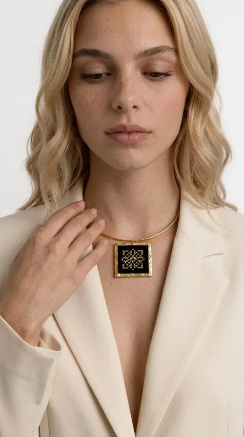 , An embroidered necklace that instantly catches every eye — this Statement Necklace with geometric patterns on a black background blends the traditional art of embroidery with a modern, minimal aesthetic.

Designed by Greek Jewelry Designer Aikaterini Chalkiadaki, this handmade necklace is a unique piece that showcases Greek craftsmanship in all its glory. The square pendant, made of brass and fabric, features an intricately worked geometric motif inspired by traditional folk art — creating an effect that resembles embroidery in a black-and-gold color palette. The choker hugs the neck with elegance, while the raised gold frame of the pendant adds a distinctive depth and character to the overall look.

Ideal for casual style with a blazer or for evening looks, this striking necklace pairs equally well with a white shirt or a black dress. If you're looking for large, eye-catching necklaces with soul and story, this is the answer.