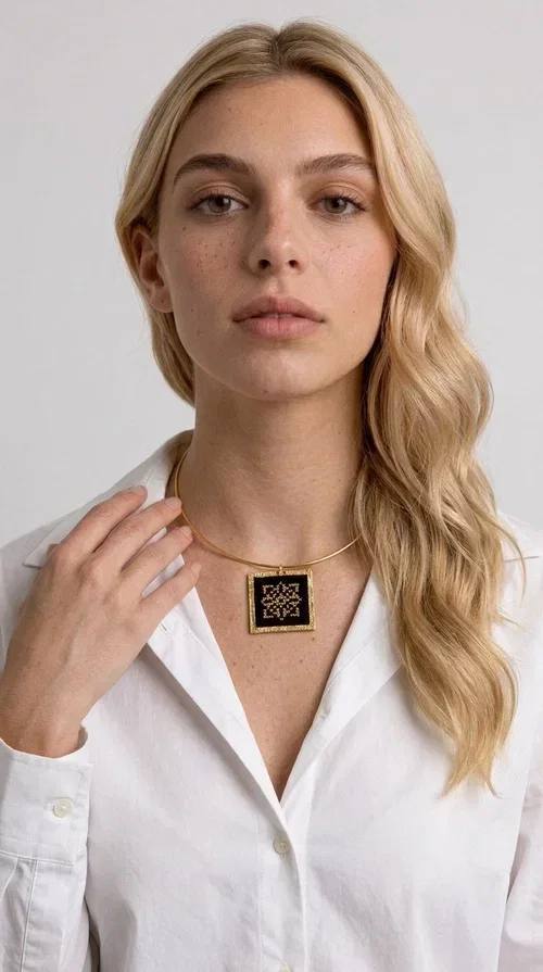 , An embroidered necklace that instantly catches every eye — this Statement Necklace with geometric patterns on a black background blends the traditional art of embroidery with a modern, minimal aesthetic.

Designed by Greek Jewelry Designer Aikaterini Chalkiadaki, this handmade necklace is a unique piece that showcases Greek craftsmanship in all its glory. The square pendant, made of brass and fabric, features an intricately worked geometric motif inspired by traditional folk art — creating an effect that resembles embroidery in a black-and-gold color palette. The choker hugs the neck with elegance, while the raised gold frame of the pendant adds a distinctive depth and character to the overall look.

Ideal for casual style with a blazer or for evening looks, this striking necklace pairs equally well with a white shirt or a black dress. If you're looking for large, eye-catching necklaces with soul and story, this is the answer.