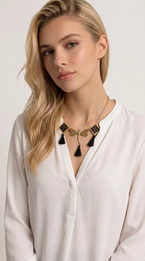, A statement embroidered necklace that instantly catches the eye — the perfect piece for every woman who wants to express herself with style and personality. Designed by Greek Jewelry Designer Aikaterini Chalkiadaki, this unique necklace combines the traditional art of embroidery with a modern, striking result. Its geometric composition and bold black palette make it a timeless statement piece that truly stands out.

The necklace features three square brass motifs with black embroidered geometric patterns, inspired by folk aesthetics. At the center sits a striking gold-tone metal element shaped like a dragonfly or butterfly, while elegant black fabric tassels hang from each motif, adding movement and lightness. The chain is gold-toned brass, durable and lightweight to wear.

Ideal for daytime looks with white or monochrome outfits, as well as for evening occasions that call for character. It pairs perfectly with simple dresses, tailored outfits, and casual looks.