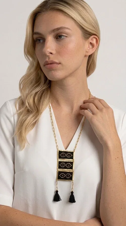 , An embroidered necklace that blends tradition with contemporary style — the Statement Necklace KOL-4754 is the perfect choice for any woman who wants to express herself through her jewelry. Designed by Greek Jewelry Designer Aikaterini Chalkiadaki, this handmade necklace features geometric embroidered patterns inspired by Greek folk tradition, creating a unique piece full of character.

Three rectangular brass frames in a gold hue are adorned with black embroidery in geometric motifs, while black tassels at the bottom add movement and dramatic flair. The gold paperclip-style chain completes the look with an elegant, modern touch. The result is a striking long necklace that suits both everyday and evening outfits equally well.

Wear it over a simple shirt or dress to create a look full of personality. It's the perfect gift choice, and also the perfect way to turn heads at an evening event.