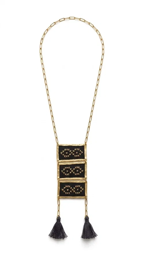 , An embroidered necklace that blends tradition with contemporary style — the Statement Necklace KOL-4754 is the perfect choice for any woman who wants to express herself through her jewelry. Designed by Greek Jewelry Designer Aikaterini Chalkiadaki, this handmade necklace features geometric embroidered patterns inspired by Greek folk tradition, creating a unique piece full of character.

Three rectangular brass frames in a gold hue are adorned with black embroidery in geometric motifs, while black tassels at the bottom add movement and dramatic flair. The gold paperclip-style chain completes the look with an elegant, modern touch. The result is a striking long necklace that suits both everyday and evening outfits equally well.

Wear it over a simple shirt or dress to create a look full of personality. It's the perfect gift choice, and also the perfect way to turn heads at an evening event.