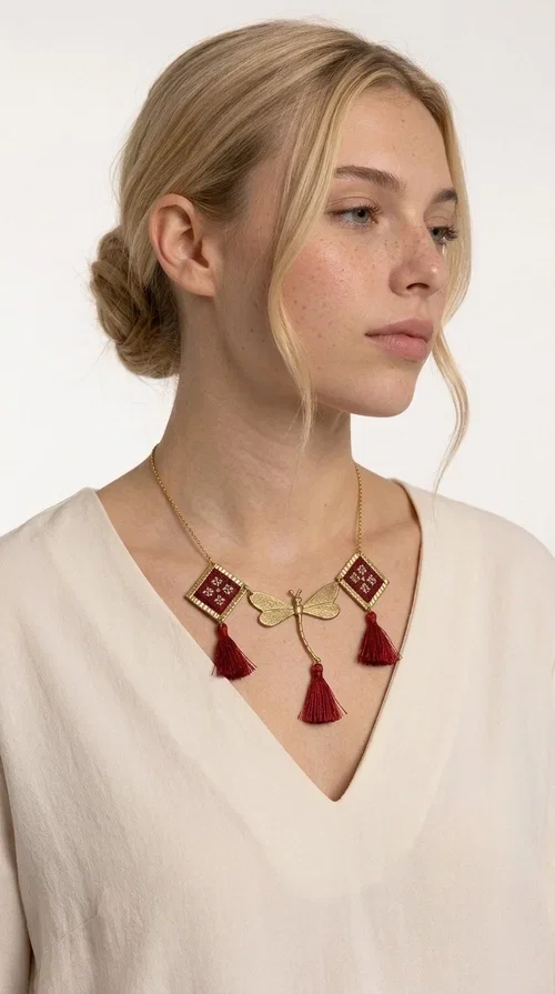 , The statement embroidered burgundy necklace is a jewel that instantly draws attention — featuring geometric patterns inspired by Greek folk art and a color palette that expresses richness and character. Designed by Greek Jewelry Designer Aikaterini Chalkiadaki, this handmade necklace combines gold-tone brass with embroidered fabric elements in deep burgundy, creating a result that balances between folk and contemporary style.

The necklace features two diamond-shaped pieces with embroidered geometric motifs, a central brass beetle-shaped link, and three burgundy tassels that add movement and drama to the overall look. The gold-tone brass chain completes the composition in an elegant, minimal way that lets the main elements shine. It is ideal as a statement piece for everyday looks as well as for evening occasions.

Wear it with a simple solid-colored shirt or dress to highlight its rich detail. It pairs exceptionally well with earthy tones, greens, and blacks.