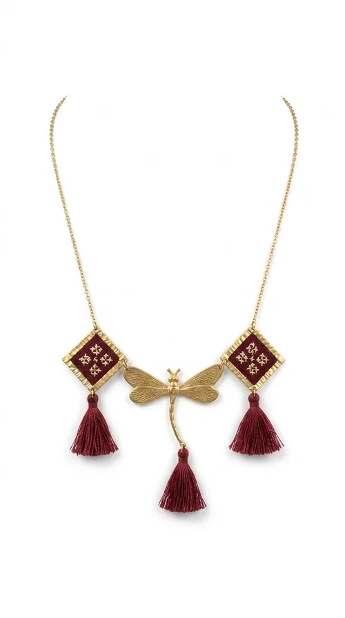 , The statement embroidered burgundy necklace is a jewel that instantly draws attention — featuring geometric patterns inspired by Greek folk art and a color palette that expresses richness and character. Designed by Greek Jewelry Designer Aikaterini Chalkiadaki, this handmade necklace combines gold-tone brass with embroidered fabric elements in deep burgundy, creating a result that balances between folk and contemporary style.

The necklace features two diamond-shaped pieces with embroidered geometric motifs, a central brass beetle-shaped link, and three burgundy tassels that add movement and drama to the overall look. The gold-tone brass chain completes the composition in an elegant, minimal way that lets the main elements shine. It is ideal as a statement piece for everyday looks as well as for evening occasions.

Wear it with a simple solid-colored shirt or dress to highlight its rich detail. It pairs exceptionally well with earthy tones, greens, and blacks.