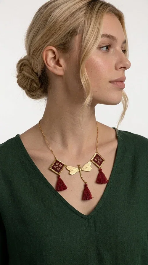 , The statement embroidered burgundy necklace is a jewel that instantly draws attention — featuring geometric patterns inspired by Greek folk art and a color palette that expresses richness and character. Designed by Greek Jewelry Designer Aikaterini Chalkiadaki, this handmade necklace combines gold-tone brass with embroidered fabric elements in deep burgundy, creating a result that balances between folk and contemporary style.

The necklace features two diamond-shaped pieces with embroidered geometric motifs, a central brass beetle-shaped link, and three burgundy tassels that add movement and drama to the overall look. The gold-tone brass chain completes the composition in an elegant, minimal way that lets the main elements shine. It is ideal as a statement piece for everyday looks as well as for evening occasions.

Wear it with a simple solid-colored shirt or dress to highlight its rich detail. It pairs exceptionally well with earthy tones, greens, and blacks.