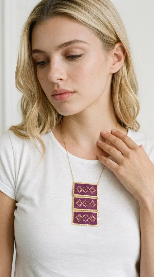 , The embroidered necklace in deep burgundy is a statement piece that instantly draws attention and transforms any outfit into something special. Designed by Greek Jewelry Designer Aikaterini Chalkiadaki, this handmade necklace combines the tradition of Greek embroidery art with a contemporary aesthetic, creating a result that is both timeless and unique.

The necklace features three rectangular fabric sections in rich burgundy, each adorned with delicate geometric patterns in gold thread — inspired by the folk tradition of Greek embroidery. The gold-toned brass frame enhances its striking presence, while the slender gold chain lends an elegant balance between bold and feminine.

Ideal for both casual and formal occasions alike, it pairs perfectly with a white t-shirt, a black dress, or even an office outfit. A perfect gift for women who love large, striking jewelry with soul and story.