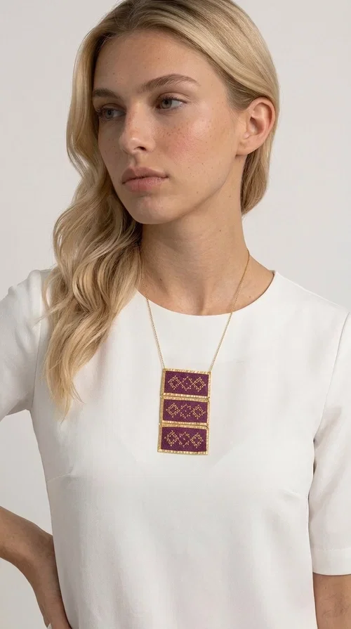 , The embroidered necklace in deep burgundy is a statement piece that instantly draws attention and transforms any outfit into something special. Designed by Greek Jewelry Designer Aikaterini Chalkiadaki, this handmade necklace combines the tradition of Greek embroidery art with a contemporary aesthetic, creating a result that is both timeless and unique.

The necklace features three rectangular fabric sections in rich burgundy, each adorned with delicate geometric patterns in gold thread — inspired by the folk tradition of Greek embroidery. The gold-toned brass frame enhances its striking presence, while the slender gold chain lends an elegant balance between bold and feminine.

Ideal for both casual and formal occasions alike, it pairs perfectly with a white t-shirt, a black dress, or even an office outfit. A perfect gift for women who love large, striking jewelry with soul and story.