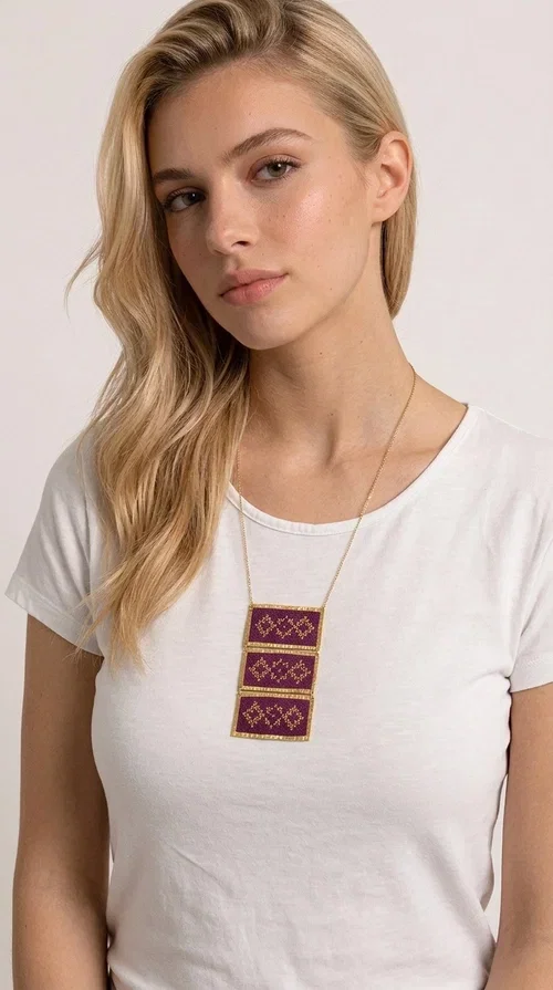 , The embroidered necklace in deep burgundy is a statement piece that instantly draws attention and transforms any outfit into something special. Designed by Greek Jewelry Designer Aikaterini Chalkiadaki, this handmade necklace combines the tradition of Greek embroidery art with a contemporary aesthetic, creating a result that is both timeless and unique.

The necklace features three rectangular fabric sections in rich burgundy, each adorned with delicate geometric patterns in gold thread — inspired by the folk tradition of Greek embroidery. The gold-toned brass frame enhances its striking presence, while the slender gold chain lends an elegant balance between bold and feminine.

Ideal for both casual and formal occasions alike, it pairs perfectly with a white t-shirt, a black dress, or even an office outfit. A perfect gift for women who love large, striking jewelry with soul and story.
