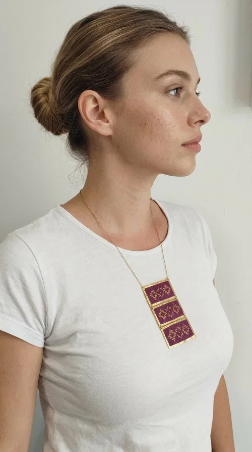 , The embroidered necklace in deep burgundy is a statement piece that instantly draws attention and transforms any outfit into something special. Designed by Greek Jewelry Designer Aikaterini Chalkiadaki, this handmade necklace combines the tradition of Greek embroidery art with a contemporary aesthetic, creating a result that is both timeless and unique.

The necklace features three rectangular fabric sections in rich burgundy, each adorned with delicate geometric patterns in gold thread — inspired by the folk tradition of Greek embroidery. The gold-toned brass frame enhances its striking presence, while the slender gold chain lends an elegant balance between bold and feminine.

Ideal for both casual and formal occasions alike, it pairs perfectly with a white t-shirt, a black dress, or even an office outfit. A perfect gift for women who love large, striking jewelry with soul and story.
