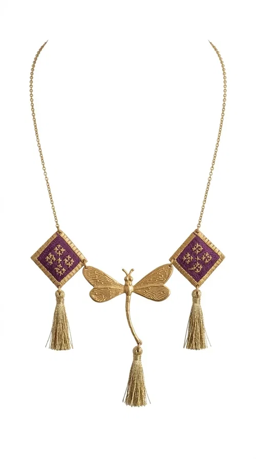 , A statement embroidered necklace that combines the traditional art of embroidery with modern aesthetics — ideal for every woman who wants to express herself with style and originality. Designed by Greek Jewelry Designer Aikaterini Chalkiadaki, this handmade necklace is a true piece of wearable art, inspired by folk heritage and the geometric motifs of Greek tradition.

The necklace features two embroidered square elements in deep burgundy color with gold geometric patterns, joined by a central gold butterfly-shaped motif made of brass. Three gold tassels hang lightly, adding movement and charm to the whole. The gold-tone brass chain completes the elegant, striking look.

It pairs perfectly over simple, solid-colored outfits — such as a blue v-neck top — instantly adding character to your look. Suitable for daytime appearances, nights out, and as a unique gift for women who love striking, feminine jewelry.