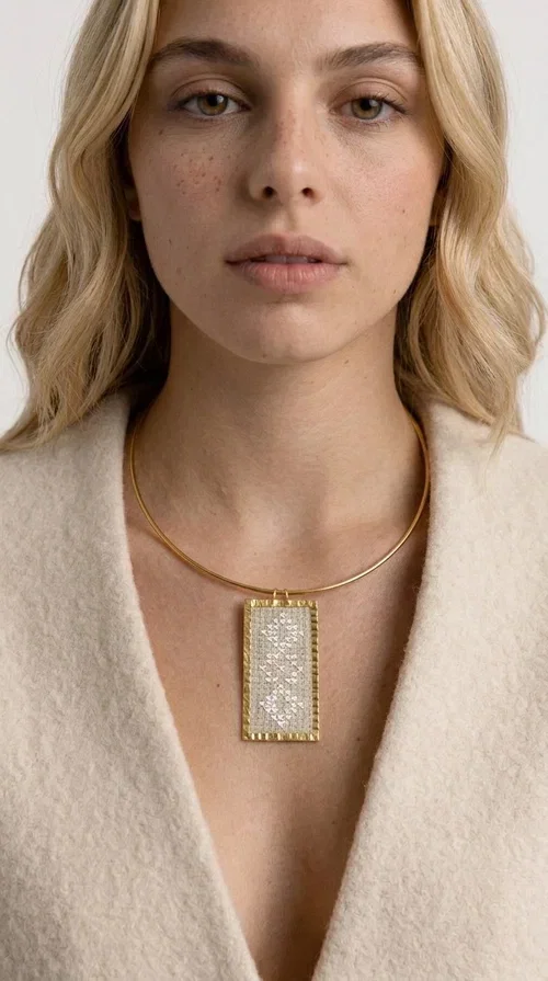 , A statement embroidered necklace that instantly catches the eye — featuring geometric patterns in cream tones and an aesthetic that blends folk tradition with contemporary style. Designed by Greek Jewelry Designer Aikaterini Chalkiadaki, this handmade piece is a distinctive choice for those seeking something beyond the ordinary.

The rectangular embroidered pendant in cream-gold tones is crafted from brass and fabric, featuring dense embroidery in geometric motifs reminiscent of folklore aesthetics. It hangs from a delicate gold-toned choker-torque style chain that elegantly and strikingly highlights the neckline. The extensive decoration with small shimmering elements adds richness and depth to the overall composition.

Ideal for casual chic or smart casual looks, it pairs beautifully with a white T-shirt, a blazer, or a summer dress. It also makes an excellent gift idea for women who appreciate handmade jewelry with a distinctive character.
