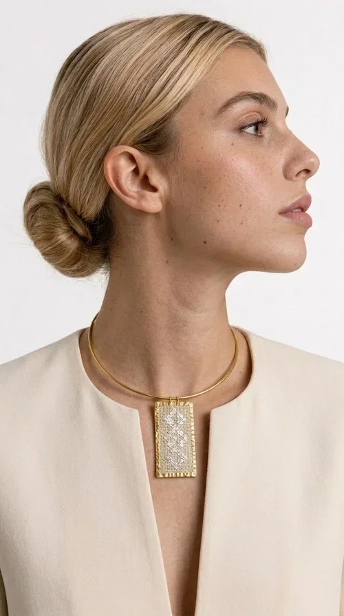 , A statement embroidered necklace that instantly catches the eye — featuring geometric patterns in cream tones and an aesthetic that blends folk tradition with contemporary style. Designed by Greek Jewelry Designer Aikaterini Chalkiadaki, this handmade piece is a distinctive choice for those seeking something beyond the ordinary.

The rectangular embroidered pendant in cream-gold tones is crafted from brass and fabric, featuring dense embroidery in geometric motifs reminiscent of folklore aesthetics. It hangs from a delicate gold-toned choker-torque style chain that elegantly and strikingly highlights the neckline. The extensive decoration with small shimmering elements adds richness and depth to the overall composition.

Ideal for casual chic or smart casual looks, it pairs beautifully with a white T-shirt, a blazer, or a summer dress. It also makes an excellent gift idea for women who appreciate handmade jewelry with a distinctive character.