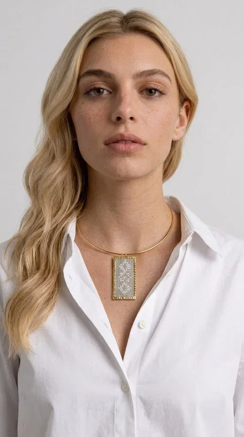 , A statement embroidered necklace that instantly catches the eye — featuring geometric patterns in cream tones and an aesthetic that blends folk tradition with contemporary style. Designed by Greek Jewelry Designer Aikaterini Chalkiadaki, this handmade piece is a distinctive choice for those seeking something beyond the ordinary.

The rectangular embroidered pendant in cream-gold tones is crafted from brass and fabric, featuring dense embroidery in geometric motifs reminiscent of folklore aesthetics. It hangs from a delicate gold-toned choker-torque style chain that elegantly and strikingly highlights the neckline. The extensive decoration with small shimmering elements adds richness and depth to the overall composition.

Ideal for casual chic or smart casual looks, it pairs beautifully with a white T-shirt, a blazer, or a summer dress. It also makes an excellent gift idea for women who appreciate handmade jewelry with a distinctive character.