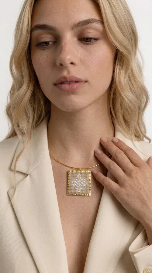 , An embroidered necklace that blends tradition with contemporary design — the Statement necklace KOL-4728 is the ideal choice for every woman who wants to express herself through unique jewelry. Designed by Greek Jewelry Designer Aikaterini Chalkiadaki, this striking necklace showcases the charm of craftsmanship in a completely modern way.

The square pendant in gold brass features delicate embroidery in a cream shade, with geometric patterns inspired by Greek folk tradition. The texture of the fabric combined with the metal frame creates a contrast that immediately catches the eye. The necklace hangs from a slender gold ring that elevates any outfit.

Ideal as a statement necklace for casual looks as well as more formal occasions, it pairs perfectly with a white t-shirt, blazer, or boho dress. It offers a boho-chic result with folklore aesthetic references, making it stand out among women's necklaces.