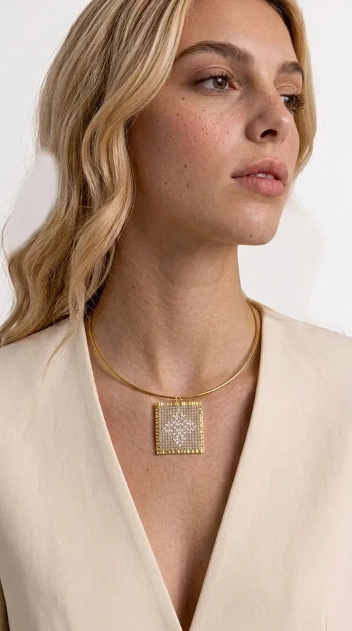 , An embroidered necklace that blends tradition with contemporary design — the Statement necklace KOL-4728 is the ideal choice for every woman who wants to express herself through unique jewelry. Designed by Greek Jewelry Designer Aikaterini Chalkiadaki, this striking necklace showcases the charm of craftsmanship in a completely modern way.

The square pendant in gold brass features delicate embroidery in a cream shade, with geometric patterns inspired by Greek folk tradition. The texture of the fabric combined with the metal frame creates a contrast that immediately catches the eye. The necklace hangs from a slender gold ring that elevates any outfit.

Ideal as a statement necklace for casual looks as well as more formal occasions, it pairs perfectly with a white t-shirt, blazer, or boho dress. It offers a boho-chic result with folklore aesthetic references, making it stand out among women's necklaces.