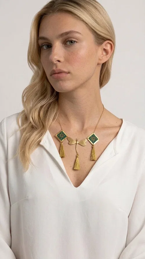 , A statement embroidered necklace that doesn't go unnoticed — featuring geometric patterns inspired by Greek tradition and a contemporary aesthetic that suits every strong feminine presence.

Designed by Greek Jewelry Designer Aikaterini Chalkiadaki, this handmade necklace combines brass and fabric in a composition strongly reminiscent of traditional folk embroidery art. Two diamond shapes of green embroidered fabric with gold geometric motifs frame a gold dragonfly at the center, while three gold tassels add movement and grace to the overall design. The result is a piece of jewelry with a deeply folklore aesthetic and, at the same time, a distinctly modern character.

Ideal for women who love striking jewelry that tells a story. It pairs perfectly with simple, monochrome looks — such as a white or cream shirt — highlighting its color and patterns. Suitable for both daytime and evening looks, receptions, weddings, or trips where you want to stand out.