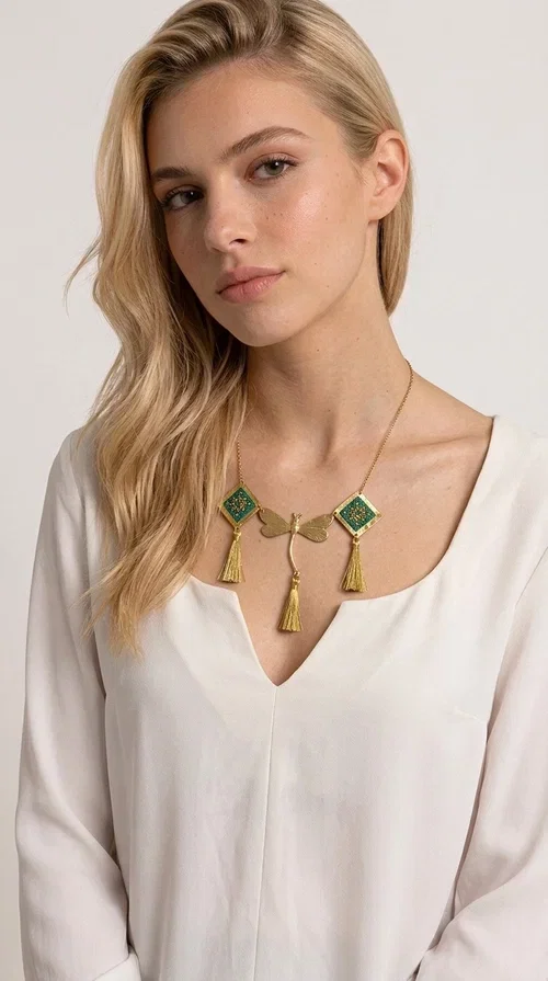 , A statement embroidered necklace that doesn't go unnoticed — featuring geometric patterns inspired by Greek tradition and a contemporary aesthetic that suits every strong feminine presence.

Designed by Greek Jewelry Designer Aikaterini Chalkiadaki, this handmade necklace combines brass and fabric in a composition strongly reminiscent of traditional folk embroidery art. Two diamond shapes of green embroidered fabric with gold geometric motifs frame a gold dragonfly at the center, while three gold tassels add movement and grace to the overall design. The result is a piece of jewelry with a deeply folklore aesthetic and, at the same time, a distinctly modern character.

Ideal for women who love striking jewelry that tells a story. It pairs perfectly with simple, monochrome looks — such as a white or cream shirt — highlighting its color and patterns. Suitable for both daytime and evening looks, receptions, weddings, or trips where you want to stand out.