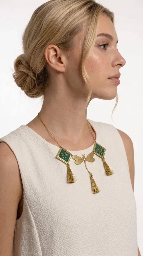 , A statement embroidered necklace that doesn't go unnoticed — featuring geometric patterns inspired by Greek tradition and a contemporary aesthetic that suits every strong feminine presence.

Designed by Greek Jewelry Designer Aikaterini Chalkiadaki, this handmade necklace combines brass and fabric in a composition strongly reminiscent of traditional folk embroidery art. Two diamond shapes of green embroidered fabric with gold geometric motifs frame a gold dragonfly at the center, while three gold tassels add movement and grace to the overall design. The result is a piece of jewelry with a deeply folklore aesthetic and, at the same time, a distinctly modern character.

Ideal for women who love striking jewelry that tells a story. It pairs perfectly with simple, monochrome looks — such as a white or cream shirt — highlighting its color and patterns. Suitable for both daytime and evening looks, receptions, weddings, or trips where you want to stand out.
