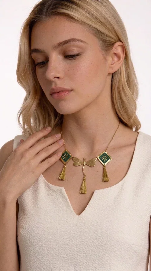 , A statement embroidered necklace that doesn't go unnoticed — featuring geometric patterns inspired by Greek tradition and a contemporary aesthetic that suits every strong feminine presence.

Designed by Greek Jewelry Designer Aikaterini Chalkiadaki, this handmade necklace combines brass and fabric in a composition strongly reminiscent of traditional folk embroidery art. Two diamond shapes of green embroidered fabric with gold geometric motifs frame a gold dragonfly at the center, while three gold tassels add movement and grace to the overall design. The result is a piece of jewelry with a deeply folklore aesthetic and, at the same time, a distinctly modern character.

Ideal for women who love striking jewelry that tells a story. It pairs perfectly with simple, monochrome looks — such as a white or cream shirt — highlighting its color and patterns. Suitable for both daytime and evening looks, receptions, weddings, or trips where you want to stand out.