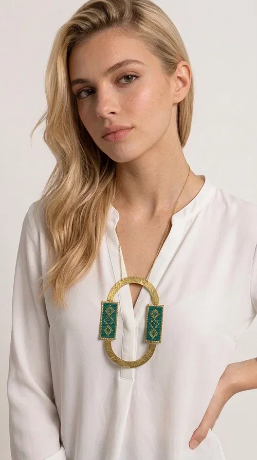 , A statement embroidered necklace that turns every look into a style declaration — featuring geometric patterns inspired by Greek folk tradition and an aesthetic that speaks for itself.

Designed by Greek Jewelry Designer Aikaterini Chalkiadaki, this long necklace combines brass and fabric in a handmade composition that highlights the art of embroidery. The oval golden brass frame embraces two rectangular fabric elements in deep green, adorned with gold-toned geometric motifs reminiscent of traditional embroidery techniques. The result is a jewelry piece with strong character, blending tradition with contemporary aesthetics.

Ideal for women who love striking jewelry, this long green necklace pairs perfectly with simple outfits — a white t-shirt, a solid-color dress, or a chic blazer. It instantly adds color, geometry, and personality to any ensemble, summer and winter alike.