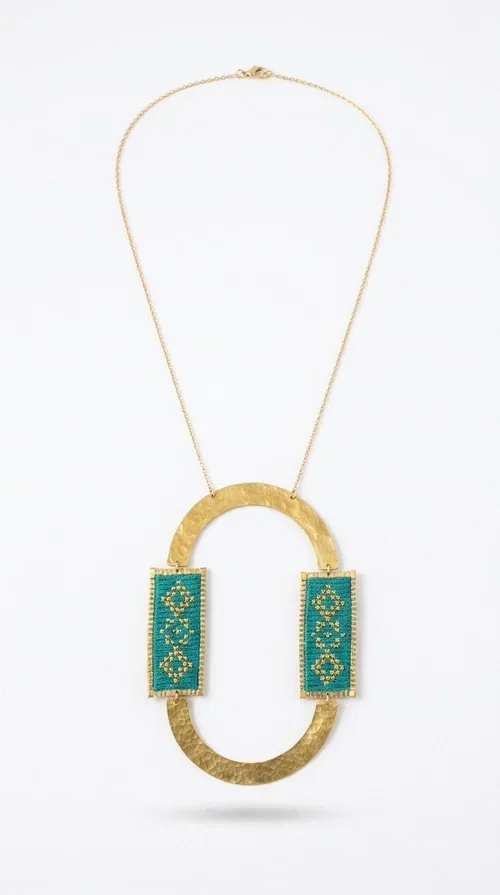 , A statement embroidered necklace that turns every look into a style declaration — featuring geometric patterns inspired by Greek folk tradition and an aesthetic that speaks for itself.

Designed by Greek Jewelry Designer Aikaterini Chalkiadaki, this long necklace combines brass and fabric in a handmade composition that highlights the art of embroidery. The oval golden brass frame embraces two rectangular fabric elements in deep green, adorned with gold-toned geometric motifs reminiscent of traditional embroidery techniques. The result is a jewelry piece with strong character, blending tradition with contemporary aesthetics.

Ideal for women who love striking jewelry, this long green necklace pairs perfectly with simple outfits — a white t-shirt, a solid-color dress, or a chic blazer. It instantly adds color, geometry, and personality to any ensemble, summer and winter alike.