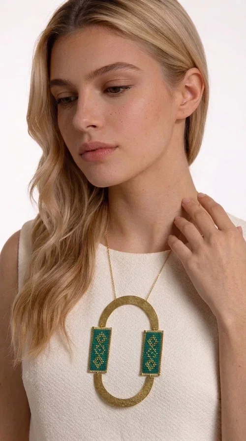 , A statement embroidered necklace that turns every look into a style declaration — featuring geometric patterns inspired by Greek folk tradition and an aesthetic that speaks for itself.

Designed by Greek Jewelry Designer Aikaterini Chalkiadaki, this long necklace combines brass and fabric in a handmade composition that highlights the art of embroidery. The oval golden brass frame embraces two rectangular fabric elements in deep green, adorned with gold-toned geometric motifs reminiscent of traditional embroidery techniques. The result is a jewelry piece with strong character, blending tradition with contemporary aesthetics.

Ideal for women who love striking jewelry, this long green necklace pairs perfectly with simple outfits — a white t-shirt, a solid-color dress, or a chic blazer. It instantly adds color, geometry, and personality to any ensemble, summer and winter alike.