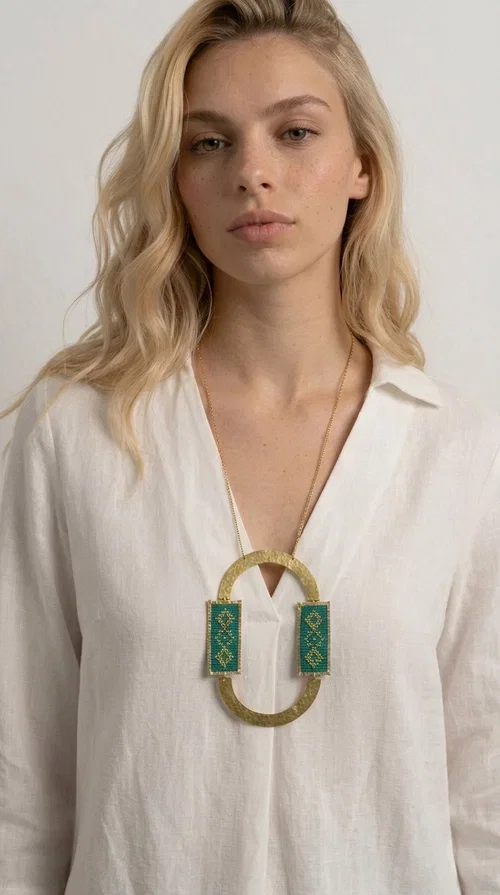 , A statement embroidered necklace that turns every look into a style declaration — featuring geometric patterns inspired by Greek folk tradition and an aesthetic that speaks for itself.

Designed by Greek Jewelry Designer Aikaterini Chalkiadaki, this long necklace combines brass and fabric in a handmade composition that highlights the art of embroidery. The oval golden brass frame embraces two rectangular fabric elements in deep green, adorned with gold-toned geometric motifs reminiscent of traditional embroidery techniques. The result is a jewelry piece with strong character, blending tradition with contemporary aesthetics.

Ideal for women who love striking jewelry, this long green necklace pairs perfectly with simple outfits — a white t-shirt, a solid-color dress, or a chic blazer. It instantly adds color, geometry, and personality to any ensemble, summer and winter alike.