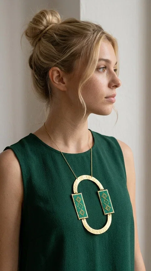 , A statement embroidered necklace that turns every look into a style declaration — featuring geometric patterns inspired by Greek folk tradition and an aesthetic that speaks for itself.

Designed by Greek Jewelry Designer Aikaterini Chalkiadaki, this long necklace combines brass and fabric in a handmade composition that highlights the art of embroidery. The oval golden brass frame embraces two rectangular fabric elements in deep green, adorned with gold-toned geometric motifs reminiscent of traditional embroidery techniques. The result is a jewelry piece with strong character, blending tradition with contemporary aesthetics.

Ideal for women who love striking jewelry, this long green necklace pairs perfectly with simple outfits — a white t-shirt, a solid-color dress, or a chic blazer. It instantly adds color, geometry, and personality to any ensemble, summer and winter alike.