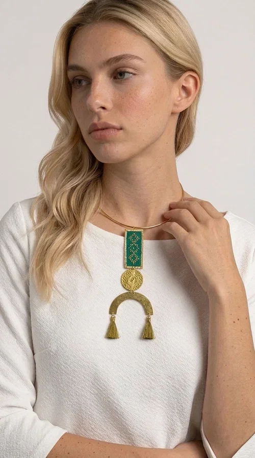 , A statement embroidered necklace that instantly catches the eye — featuring a bold green color, geometric patterns and gold details reminiscent of the tradition of folk jewelry.

Designed by Greek Jewelry Designer Aikaterini Chalkiadaki, this handmade necklace combines brass and fabric in a composition that highlights the skill of Greek craftsmanship. The rectangular embroidered piece, with its delicate geometric motifs in gold and green tones, blends harmoniously with a gold circular disc and a brass arc, while three hanging tassels in a khaki-gold shade add movement and warmth to the overall look. It is worn on a gold rigid choker for an even more striking effect.

Ideal for looks that want to stand out — from summer evening outings to casual chic styles with simple linen or cotton clothing. It pairs perfectly with neutral tones, white, ecru, or deep green shades.