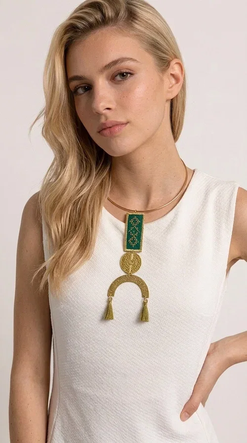 , A statement embroidered necklace that instantly catches the eye — featuring a bold green color, geometric patterns and gold details reminiscent of the tradition of folk jewelry.

Designed by Greek Jewelry Designer Aikaterini Chalkiadaki, this handmade necklace combines brass and fabric in a composition that highlights the skill of Greek craftsmanship. The rectangular embroidered piece, with its delicate geometric motifs in gold and green tones, blends harmoniously with a gold circular disc and a brass arc, while three hanging tassels in a khaki-gold shade add movement and warmth to the overall look. It is worn on a gold rigid choker for an even more striking effect.

Ideal for looks that want to stand out — from summer evening outings to casual chic styles with simple linen or cotton clothing. It pairs perfectly with neutral tones, white, ecru, or deep green shades.