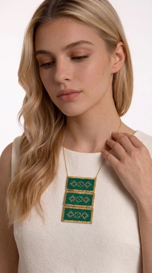 , An embroidered green necklace that blends tradition with contemporary design — ideal for those who want to make a statement in a truly unique way. Designed by Greek Jewelry Designer Aikaterini Chalkiadaki, this striking necklace brings a breath of fresh air to the world of handmade jewelry. The deep green fabric combined with golden geometric embroidered motifs creates a sense of richness and authenticity rarely found in mass-produced jewelry.

The necklace is made of three rectangular brass sections, covered in green fabric and adorned with embroidered geometric patterns inspired by Greek folk tradition (folklore). The delicate gold chain that accompanies it adds grace and balance, making it ideal for both daytime looks and evening outings. It pairs perfectly with white, ecru, or monochrome outfits, instantly adding character to any look.