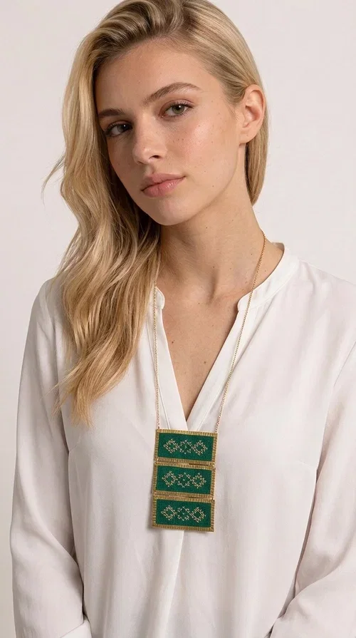 , An embroidered green necklace that blends tradition with contemporary design — ideal for those who want to make a statement in a truly unique way. Designed by Greek Jewelry Designer Aikaterini Chalkiadaki, this striking necklace brings a breath of fresh air to the world of handmade jewelry. The deep green fabric combined with golden geometric embroidered motifs creates a sense of richness and authenticity rarely found in mass-produced jewelry.

The necklace is made of three rectangular brass sections, covered in green fabric and adorned with embroidered geometric patterns inspired by Greek folk tradition (folklore). The delicate gold chain that accompanies it adds grace and balance, making it ideal for both daytime looks and evening outings. It pairs perfectly with white, ecru, or monochrome outfits, instantly adding character to any look.