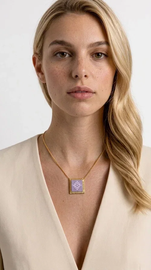 , The embroidered lilac necklace with geometric patterns is a statement piece that combines the traditional art of embroidery with a modern aesthetic, creating a result that instantly stands out. Designed by Greek Jewelry Designer Aikaterini Chalkiadaki, this handmade necklace is the perfect blend of folklore inspiration and contemporary style.

The rectangular pendant in lilac shades features detailed geometric motifs embroidered on fabric, framed by gold-tone brass that adds elegance and structure. The gold box chain harmoniously completes the look, while the larger size of the pendant makes it ideal for those who want to make a statement with their style.

Wear it with casual or formal outfits — it pairs equally well with a linen dress for a summer stroll and a blazer for a professional look. An ideal gift for every woman who loves unique, handmade jewelry with a Greek soul.