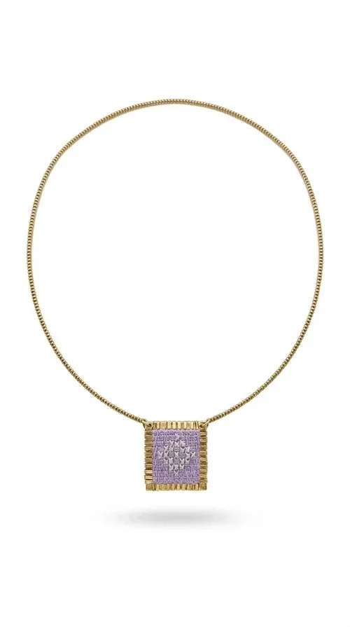 , The embroidered lilac necklace with geometric patterns is a statement piece that combines the traditional art of embroidery with a modern aesthetic, creating a result that instantly stands out. Designed by Greek Jewelry Designer Aikaterini Chalkiadaki, this handmade necklace is the perfect blend of folklore inspiration and contemporary style.

The rectangular pendant in lilac shades features detailed geometric motifs embroidered on fabric, framed by gold-tone brass that adds elegance and structure. The gold box chain harmoniously completes the look, while the larger size of the pendant makes it ideal for those who want to make a statement with their style.

Wear it with casual or formal outfits — it pairs equally well with a linen dress for a summer stroll and a blazer for a professional look. An ideal gift for every woman who loves unique, handmade jewelry with a Greek soul.
