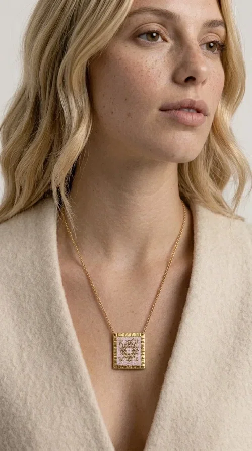 , An embroidered necklace that combines the traditional art of embroidery with a modern aesthetic — ideal for every woman who loves statement jewelry with character. Designed by Greek Jewelry Designer Aikaterini Chalkiadaki, this handmade necklace is a unique example of folklore-inspired aesthetics drawing from Greek tradition.

The square pendant in pink and gold tones is adorned with geometric patterns embroidered on fabric, set into a gold-tone brass base with a textured surface. The gold rolo chain gives the piece an elegant, contemporary touch that makes it easy to style — whether with an everyday casual look or an evening outfit.

The pink palette with gold embroidered details offers a warm, feminine feel, while the handmade construction guarantees uniqueness. An ideal gift for women who appreciate jewelry with history and soul.