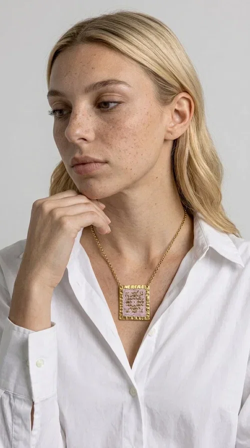 , An embroidered necklace that combines the traditional art of embroidery with a modern aesthetic — ideal for every woman who loves statement jewelry with character. Designed by Greek Jewelry Designer Aikaterini Chalkiadaki, this handmade necklace is a unique example of folklore-inspired aesthetics drawing from Greek tradition.

The square pendant in pink and gold tones is adorned with geometric patterns embroidered on fabric, set into a gold-tone brass base with a textured surface. The gold rolo chain gives the piece an elegant, contemporary touch that makes it easy to style — whether with an everyday casual look or an evening outfit.

The pink palette with gold embroidered details offers a warm, feminine feel, while the handmade construction guarantees uniqueness. An ideal gift for women who appreciate jewelry with history and soul.