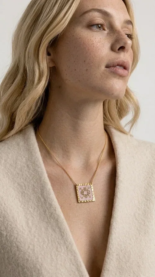 , An embroidered necklace that combines the traditional art of embroidery with a modern aesthetic — ideal for every woman who loves statement jewelry with character. Designed by Greek Jewelry Designer Aikaterini Chalkiadaki, this handmade necklace is a unique example of folklore-inspired aesthetics drawing from Greek tradition.

The square pendant in pink and gold tones is adorned with geometric patterns embroidered on fabric, set into a gold-tone brass base with a textured surface. The gold rolo chain gives the piece an elegant, contemporary touch that makes it easy to style — whether with an everyday casual look or an evening outfit.

The pink palette with gold embroidered details offers a warm, feminine feel, while the handmade construction guarantees uniqueness. An ideal gift for women who appreciate jewelry with history and soul.