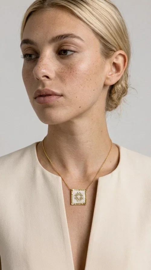 , The embroidered necklace with geometric patterns is a statement piece of jewelry that combines the traditional art of embroidery with a modern, minimal aesthetic. Designed by Greek Jewelry Designer Aikaterini Chalkiadaki, this necklace is a handmade piece with strong character — ideal for women who appreciate authenticity and want to stand out.

The square pendant is adorned with white embroidery in geometric motifs inspired by folk tradition, while the gold-toned brass frame adds warmth and elevates the level of elegance. The gold-tone chain blends softly into the overall look, creating a piece of jewelry that suits casual looks just as well as formal occasions.

Wear it over a white t-shirt or under a blazer for an effortless chic look. It also makes a wonderful gift for women who love handmade jewelry with a Greek identity.