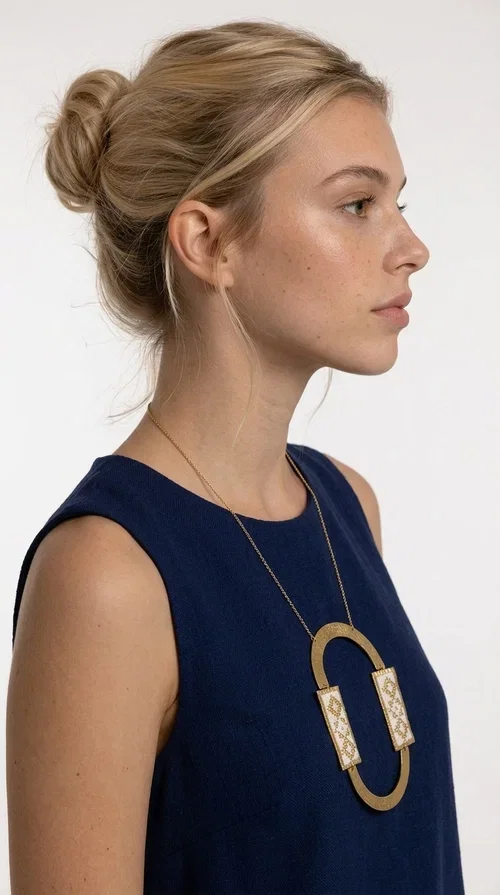 , An embroidered necklace that blends tradition with modern design — the Statement necklace KOL-4745 is the ideal choice for every woman who wants to express herself with style and authenticity.

Designed by Greek Jewelry Designer Aikaterini Chalkiadaki, this striking long necklace features a handmade oval brass element in a gold tone, framed by two rectangular embroidered plaques made of white fabric with geometric patterns inspired by Greek folk tradition. The gold-tone chain adds an elegant, modern touch, while the embroidered motifs bring a warm, handcrafted feel.

Perfect for pairing with simple outfits in neutral shades — such as khaki, white or beige — it turns any look into a true statement. Suitable for both everyday wear and special evening occasions.