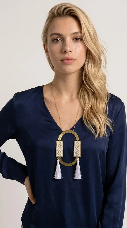 , An embroidered necklace that combines tradition with contemporary design — the Statement Necklace KOL-4757 is the ideal choice for every woman who wants to express herself through her jewelry. Designed by Greek Jewelry Designer Aikaterini Chalkiadaki, this handmade necklace is a unique combination of fabric and brass, inspired by folk art and the geometric motifs of Greek tradition.

Two embroidered rectangular plates with geometric patterns in white and gold frame a hammered gold brass circle, while three light-colored tassels add movement and character. The long gold chain completes a composition that is both statement-making and harmonious. Ideal for summer looks, casual outfits, and evening moments when you want to stand out.