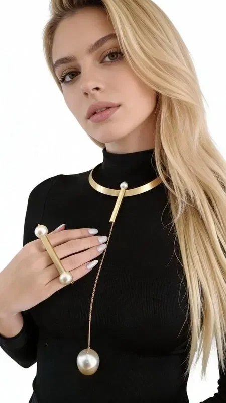 , Discover the unique beauty of this statement long necklace with pearls, a striking piece of jewelry that combines elegance with a modern aesthetic. Designed by Greek Jewelry Designer Aikaterini Chalkiadaki, this handmade necklace is the perfect choice for women who love eye-catching accessories.

The long necklace features a minimalist gold collar that holds an elegant pearl pendant, creating a statement look that stands out. The geometric line and golden hue add modern luxury, while the pearl at the bottom adds femininity and elegance.

Ideal for layering with other necklaces or wearing on its own for special occasions, this neck jewelry becomes the focal point of any look. It pairs perfectly with both casual and elegant outfits, from sweaters to dresses.

Care for your necklace by storing it in a dry place and gently cleaning it with a soft cloth.