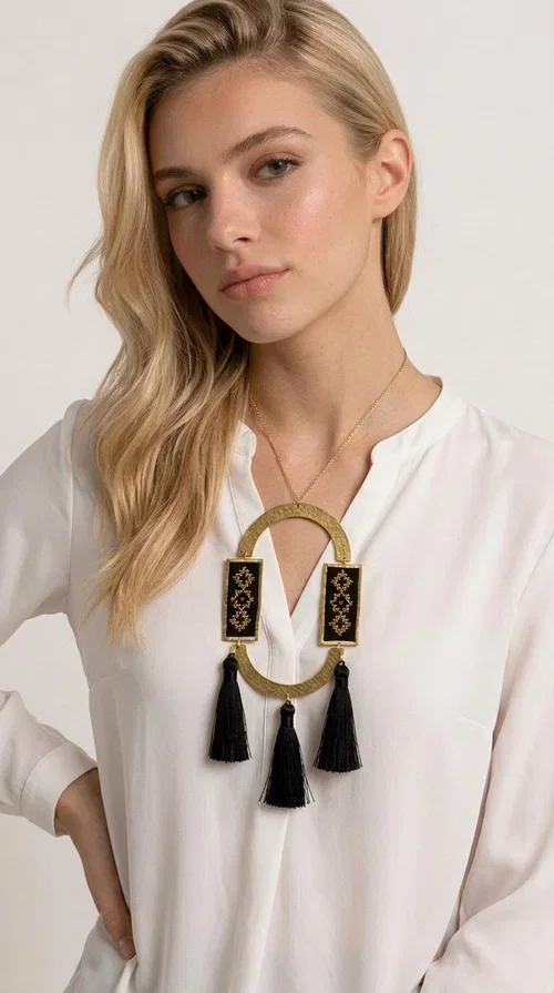 , A statement embroidered necklace that blends tradition with modern aesthetics — ideal for every woman who wants to express herself with style and character.

Designed by Greek Jewelry Designer Aikaterini Chalkiadaki, this striking long necklace is an ode to folk art and craftsmanship. Two rectangular embroidered plaques with geometric patterns in black and gold are framed by a golden brass arch, while three black tassels add movement and boho-chic charm. The gold-tone chain completes the composition with an elegant finishing touch.

This embroidered necklace pairs beautifully with simple white or ecru outfits that let the piece take center stage, as well as with evening looks that need that extra touch. Worn alone, it instantly turns any look into a statement.