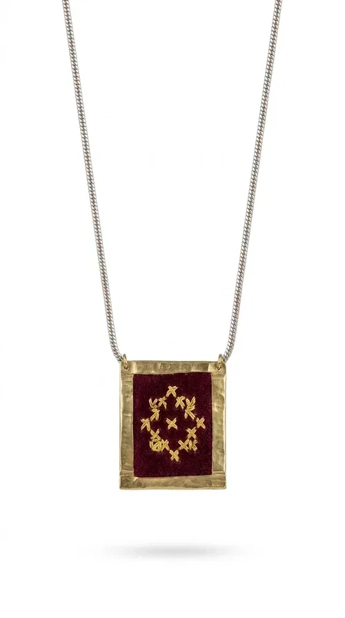 , The embroidered burgundy necklace with geometric patterns is a statement piece that combines the traditional art of embroidery with a contemporary aesthetic, creating a unique result that instantly catches the eye.

Designed by Greek Jewelry Designer Aikaterini Chalkiadaki, this handmade necklace features a square brass pendant with deep burgundy fabric and a striking embroidered geometric motif inspired by Greek folk tradition. The gold-toned brass metal frame surrounds the embroidery, giving the piece a vintage, luxurious feel. The delicate gold-tone chain highlights the pendant, making it the ultimate focal point of any look.

Ideal for pairing with a casual white shirt, a dress, or elegant attire for an evening out, this necklace is equally suited to everyday and formal occasions. It also makes an excellent gift choice for loved ones who appreciate unique, handmade jewelry with a Greek soul.