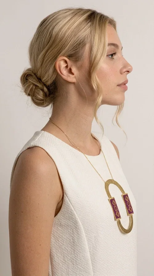 , An embroidered necklace that instantly catches the eye — the Statement Necklace KOL-4753 combines the tradition of Greek embroidery art with a modern, geometric aesthetic. Designed by Greek Jewelry Designer Aikaterini Chalkiadaki, this striking long necklace is the ultimate statement piece for every woman who appreciates handmade artistry and uniqueness.

The necklace features two rectangular fabric elements in deep burgundy, adorned with gold embroidery of geometric patterns inspired by folklore aesthetics. The embroidered sections are framed by shiny gold-toned brass, forming a large oval shape — a bold design choice that highlights the uniqueness of the piece. The gold-toned chain offers an elegant long line that pairs perfectly with simple, monochrome outfits.

Ideal for stylish daytime looks as well as evening outings, this necklace suits both casual and formal ensembles equally well. It gives your look an authentic, artistic character.