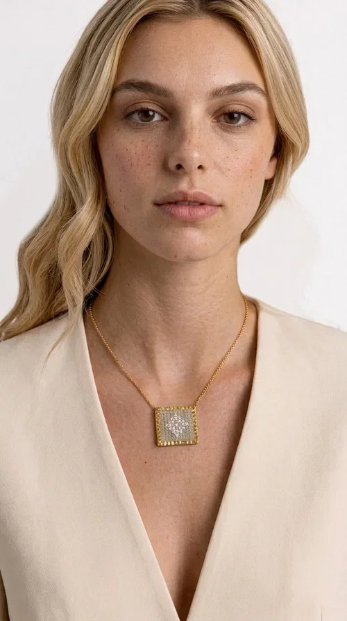 , An embroidered necklace that combines the traditional art of embroidery with a modern aesthetic — ideal for every woman who loves handmade jewelry with character.

Designed by Greek Jewelry Designer Aikaterini Chalkiadaki, this statement necklace in a cream shade features a square brass pendant with a gold finish, adorned with delicate embroidered geometric patterns on fabric. The gold-tone box chain completes the composition harmoniously, offering an air of elegance and uniqueness. Each piece is the result of handcrafted work, with attention to every detail.

This necklace pairs perfectly with casual looks as well as more formal outfits — try it over a white t-shirt for a bohemian style or combine it with a blazer for a more sophisticated look. Ideal as a gift for women who appreciate handmade jewelry and Greek craftsmanship.