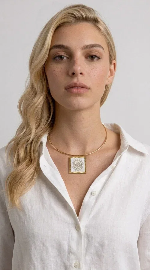, An embroidered necklace that combines tradition with modern aesthetics — the Statement Necklace KOL-4721 is a handmade creation that stands out for its refined detail and unique character. Designed by Greek Jewelry Designer Aikaterini Chalkiadaki, this piece pays tribute to the folk Greek art of embroidery, rendering geometric motifs on white fabric with gold details.

The rectangular embroidered pendant, featuring a handcrafted gold-tone brass frame, hangs from a classic gold omega-style necklace chain, which adds stability and elegance to the overall look. The folklore geometric patterns on the white fabric create an eye-catching contrast, while the overall aesthetic moves between ethnic and contemporary style.

Ideal for pairing with linen or wool clothing in neutral tones, it suits both casual and more formal looks. A true statement piece for the neck that needs no other additions to shine.