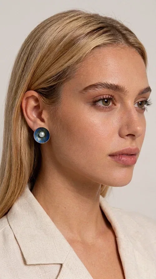 , The handmade stud earrings with a pearl in deep blue enamel are an ideal choice for every woman seeking elegance with character. Designed by Greek Jewelry Designer Aikaterini Chalkiadaki, these unique earrings combine the traditional technique of enamel with the timeless grace of the pearl, creating a result that impresses without being overwhelming.

The circular brass body is covered with handmade enamel in rich shades of blue — from deep navy to cobalt — with subtle color variations reminiscent of the ocean depths. At the center, a white pearl adds finesse and contrast, elevating the whole piece to another level. The result is a statement piece of jewelry that suits an everyday look just as well as a wedding or formal outfit.
