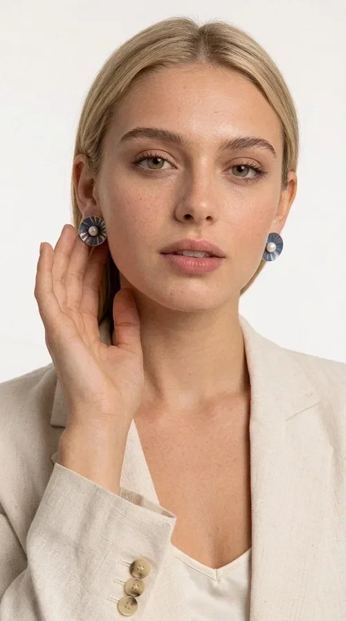 , These handmade stud earrings with pearls in deep blue color are an elegant choice for every woman seeking jewelry with character and quality. Designed by Greek Jewelry Designer Aikaterini Chalkiadaki, these earrings combine the traditional art of enamel with the timeless beauty of the pearl, creating a result that truly stands out.

The circular brass shape with a relief surface in a radiant sunburst pattern gives the piece an open, flower-like character. The blue-toned enamel evenly covers the base, while at the center a white pearl stands out, adding finesse and contrast. Their stud design makes them ideal for everyday wear, as well as for formal occasions.

Wear them paired with linen or neutral outfits to highlight their color palette, or choose them as a statement piece for weddings, christenings, and every special moment.