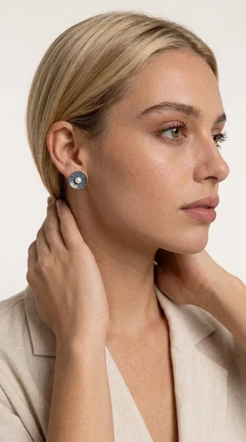 , These handmade stud earrings with pearls in deep blue color are an elegant choice for every woman seeking jewelry with character and quality. Designed by Greek Jewelry Designer Aikaterini Chalkiadaki, these earrings combine the traditional art of enamel with the timeless beauty of the pearl, creating a result that truly stands out.

The circular brass shape with a relief surface in a radiant sunburst pattern gives the piece an open, flower-like character. The blue-toned enamel evenly covers the base, while at the center a white pearl stands out, adding finesse and contrast. Their stud design makes them ideal for everyday wear, as well as for formal occasions.

Wear them paired with linen or neutral outfits to highlight their color palette, or choose them as a statement piece for weddings, christenings, and every special moment.